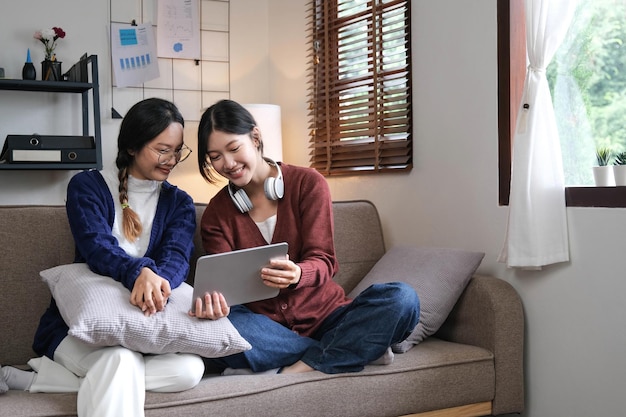 Asian beautiful lesbian women couple hugging girlfriend in living room Attractive two female gay friend sitting on sofa in living room feel happy and enjoy spending time together on holiday in house