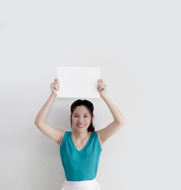 Asian beautiful woman are holding white paper or board over head for writing text or information to communicate to people