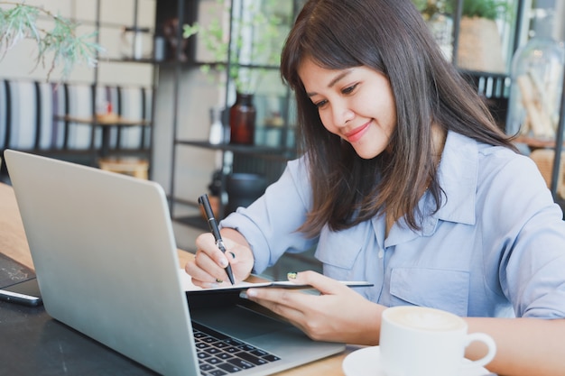 Asian beautiful woman  in blue shirt  using laptop and drinking coffee