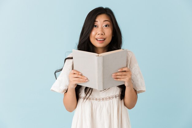 Asian beautiful woman isolated over blue wall reading book