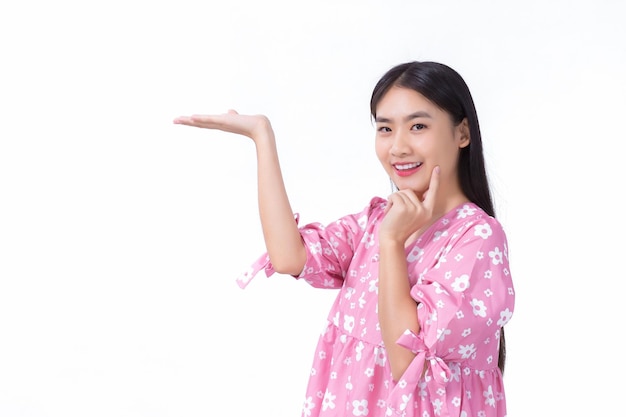 Asian beautiful woman with black long hair in pink shirt shows present something on white background