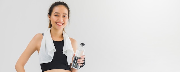 Asian beautiful women holding water bottle after play yoga and exercise on white wall background with copy spaceExercise for Lose weight increase flexibility and tighten the shape