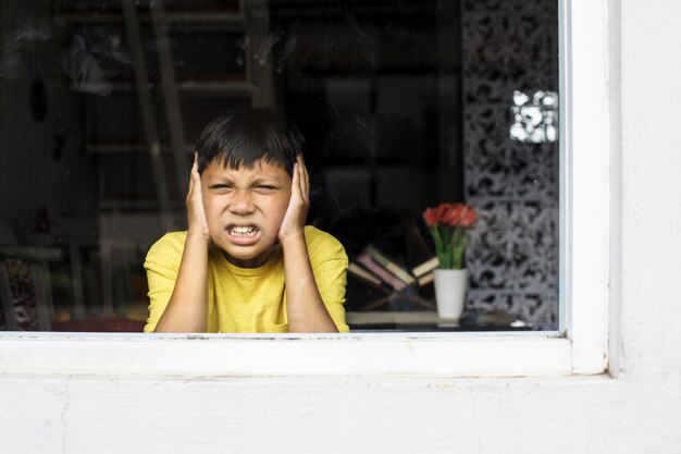 Asian boy closing ears with his hands in a protective position Childhood traumatic experience