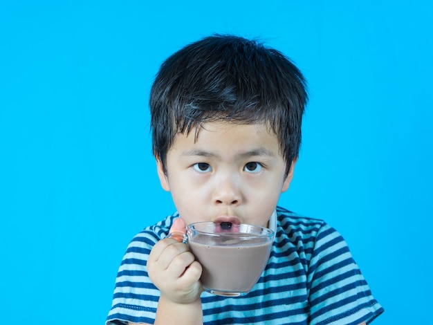 Asian Boy drinking chocolate milk on blue background