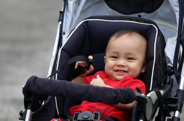 Asian boy happily sitting on a baby carriage