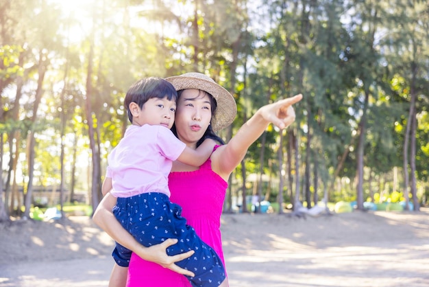 Asian boy and mom woman relaxing on tropical beach they are njoy freedom and fresh air wearing stylish hat and clothes Happy smiling tourist in tropics in travel vacation