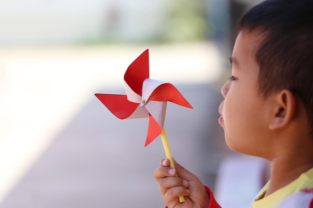 Asian boy playing with red windmill