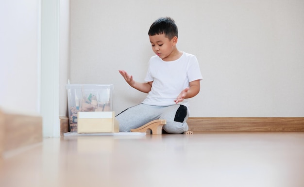 Asian boy playing wood block toy on the floor at home