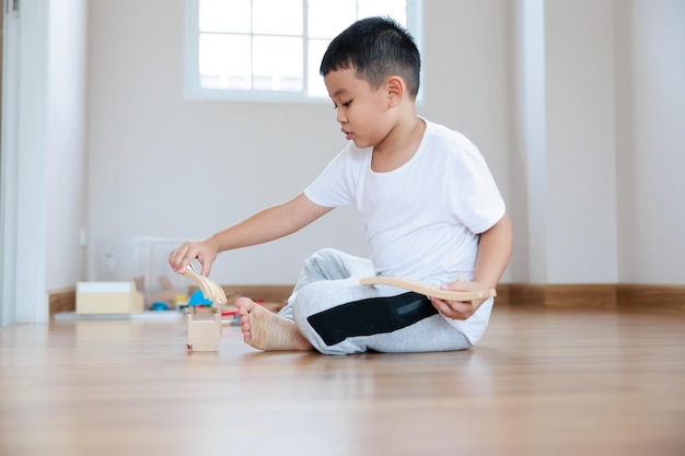 Asian boy playing wood block toy on the floor at home