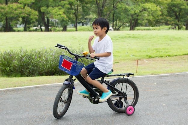 Asian boy ride a bicycle at park green nature background.