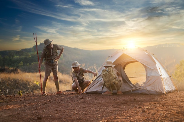 Asian Boy Scouts go camping adult mentor guides group of Boy Scouts hiking at wild nature sunset photo background