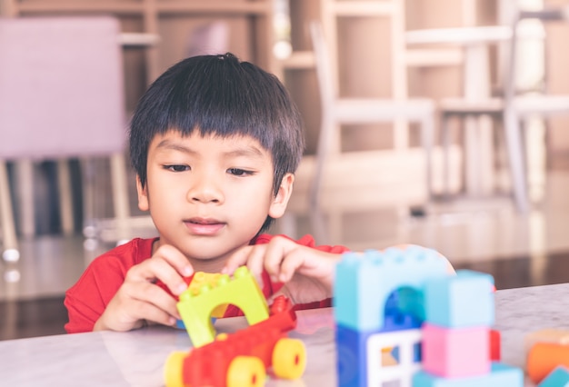 Asian boy stacking Toy blocks on a living room table