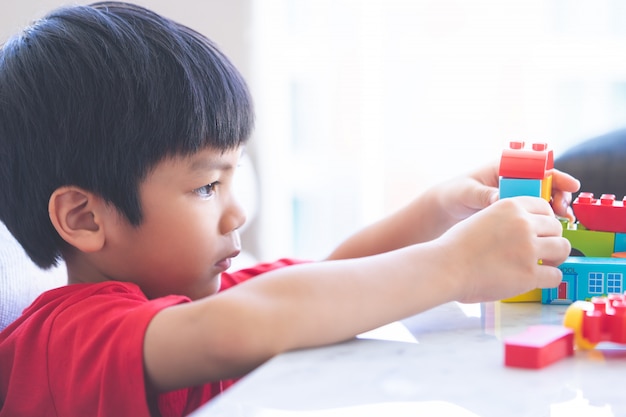 Asian boy stacking Toy blocks on a living room table