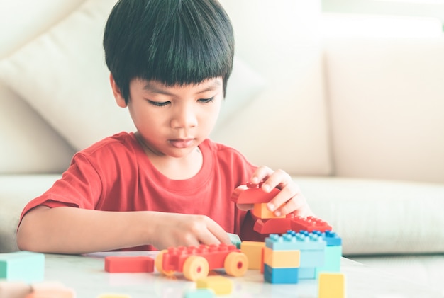 Asian boy stacking Toy blocks on a living room table