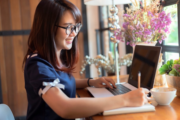 Asian business female working with make a note with a notebook and laptop