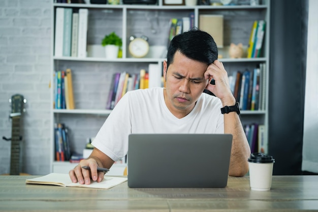 Asian Business man wear glasses and hand over head having stressful depression sad time while working on laptop at home Depression man sad serios working from home Working at anywhere concept