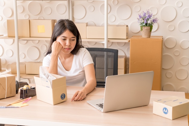 Asian business owner working at home with packing box on workplace