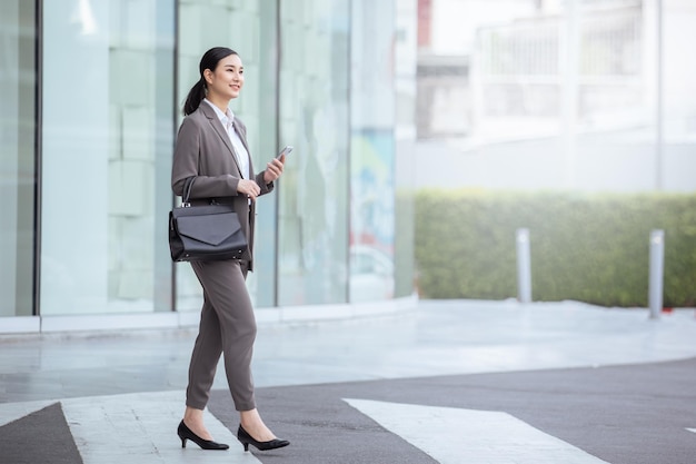 Asian business walking in casual suite with smart phone asian woman with smartphone