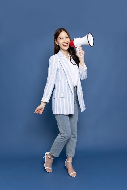 Asian business woman holding megaphone isolated on blue background