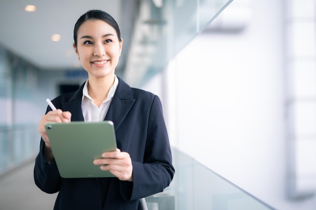 Asian business woman holding a tablet looking away , smart business concept.