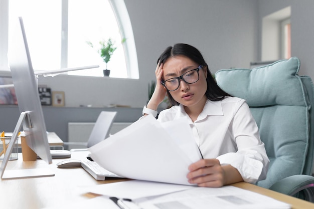 Asian business woman behind paper work tired and frustrated working in office female employee in bra