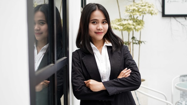 Asian business woman smiling and standing in front office