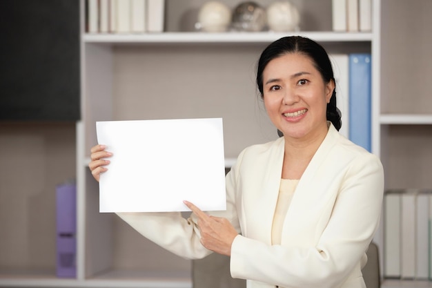 Asian Business woman standing smile hand pointing at blank paper space for text