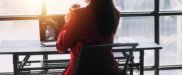 Asian Business woman using calculator and laptop for doing math finance on an office desk tax report accounting statistics and analytical research concept