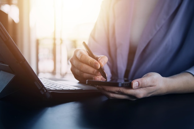 Asian Business woman using calculator and laptop for doing math finance on an office desk tax report accounting statistics and analytical research concept