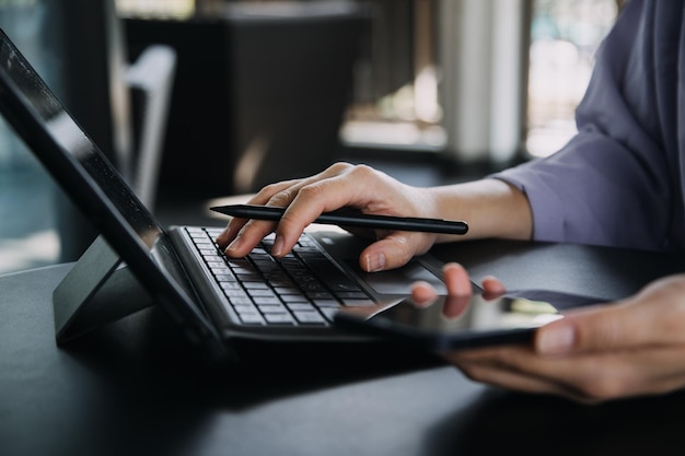 Asian Business woman using calculator and laptop for doing math finance on an office desk tax report accounting statistics and analytical research concept