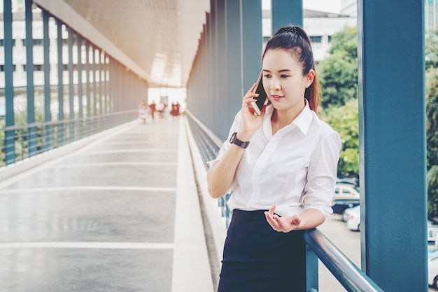 Asian business woman wearing white shirt talking smartphone for work