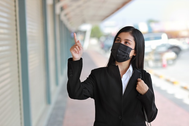 Asian business woman with protect mask for walking on street public outdoor and pointing something. 