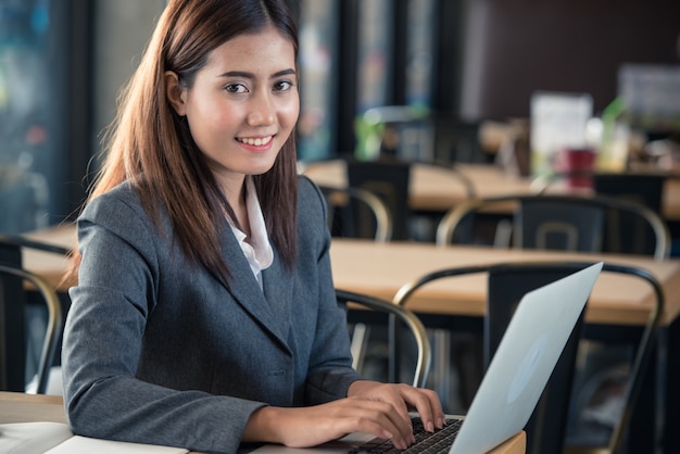 Asian business woman working on Laptop computer in the shop.