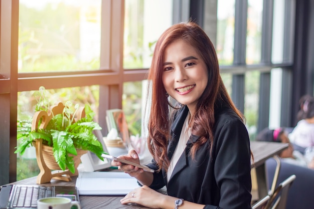 Asian business women using notebook and smart phone and business women smiling happy for working