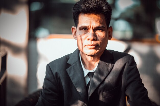 An Asian businessman in a black suit sitting at the office is stressed