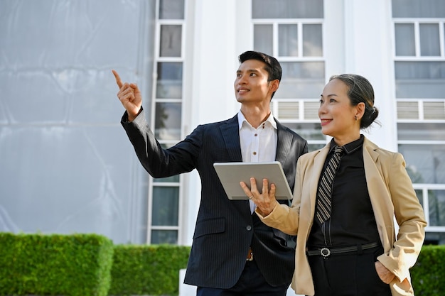 Asian businessman and confident aged asian businesswoman standing outside of the building