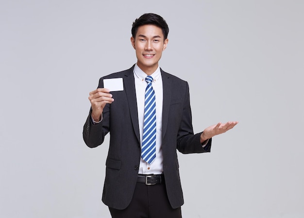 Asian businessman smile in formal suit showing mockup credit card on white background studio shot