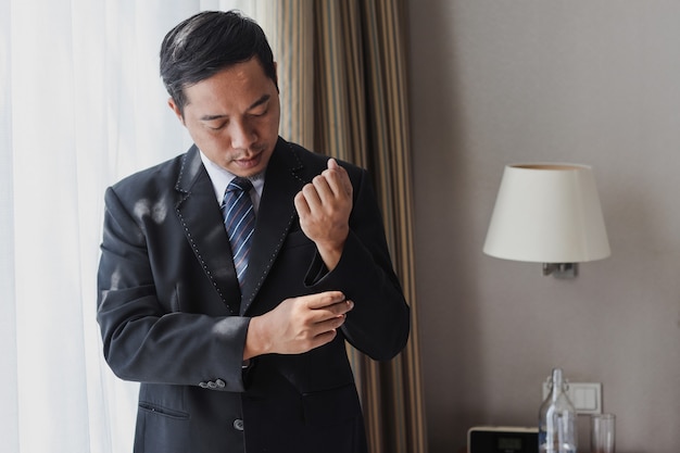 Asian Businessman tidy up and fastening button on his suit sleeve