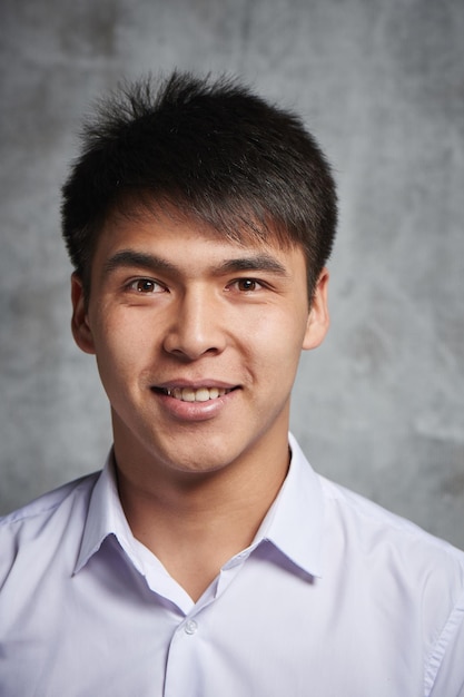 Asian businessman toothy smiling. Portrait of a young attractive Kazakh student in a white shirt in the studio