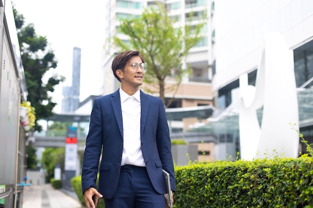 Asian businessman wearing suit jacket walking go to work in morning outdoor.