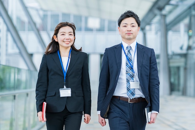 Asian businessman and woman in suits walking side by side