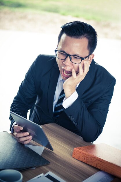 Asian Businessman working on tablet, pressured to work and unsuccessful