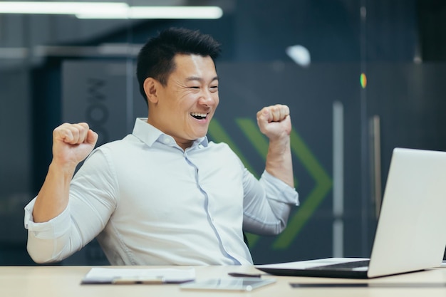 Asian businessman works in a modern office rejoices at the end of the working day and is satisfied