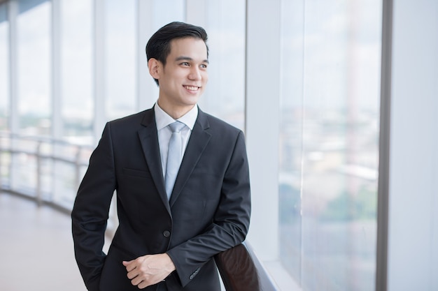 Asian Businessman young with suit looking away so felling happiness in company