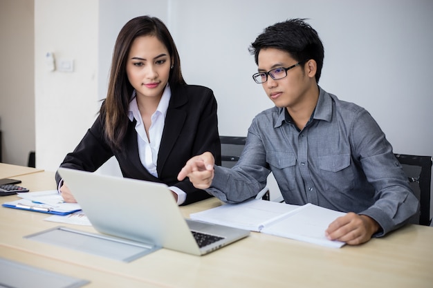 Asian businessmen and group using notebook for business partners discussing documents and ideas at meeting and business women smiling happy for working