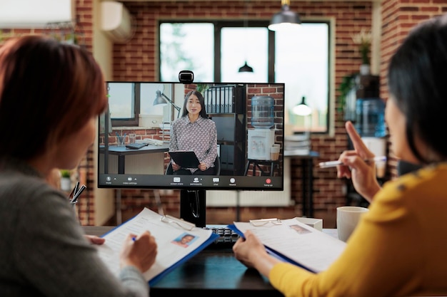 Asian businesspeople interviewing remote recruiter discussing hiring application during online videocall meeting conference. Teleconference call on computer screen in startup business office