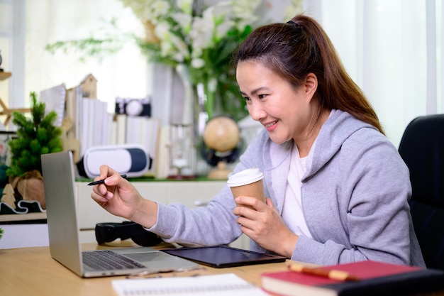 Asian businesswoman online working at home. Thai woman lifestyle in living room. Social distancing and new normal.