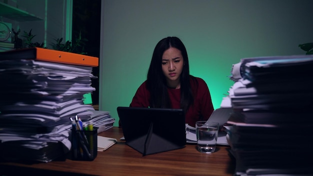 Asian businesswoman online working with tablet computer at home. Busy and exhausted of work overtime at night.