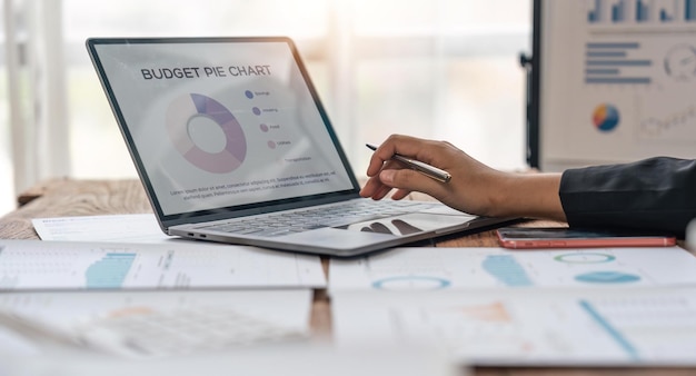 Asian businesswoman sit at their desks at office and calculate financial graphs showing results about their investments plan a successful business growth process diagrams on screen