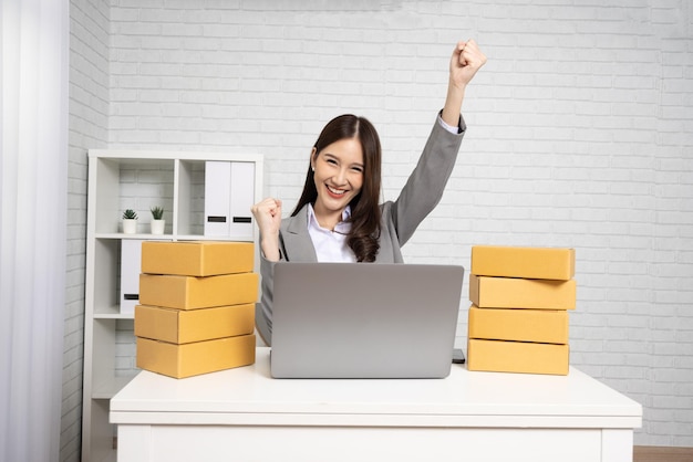 Asian businesswoman sitting with computer laptop and parcel box Successful